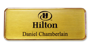 A golden plastic executive name badge with the leyend: "Hilton"